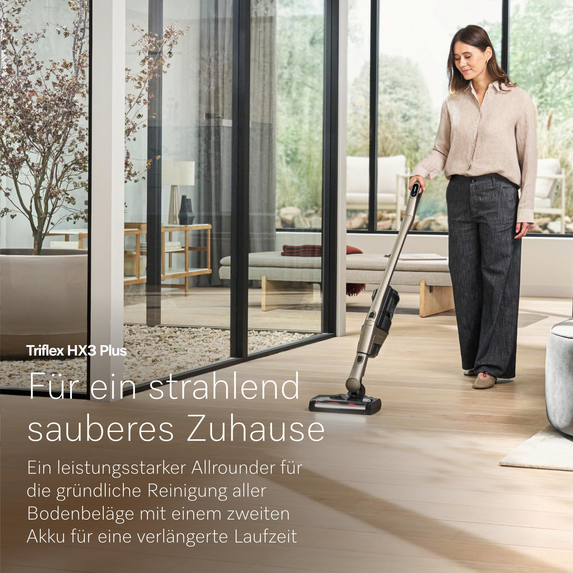 Eine Frau saugt mit einem kabellosen Staubsauger in einem modernen Wohnzimmer.
