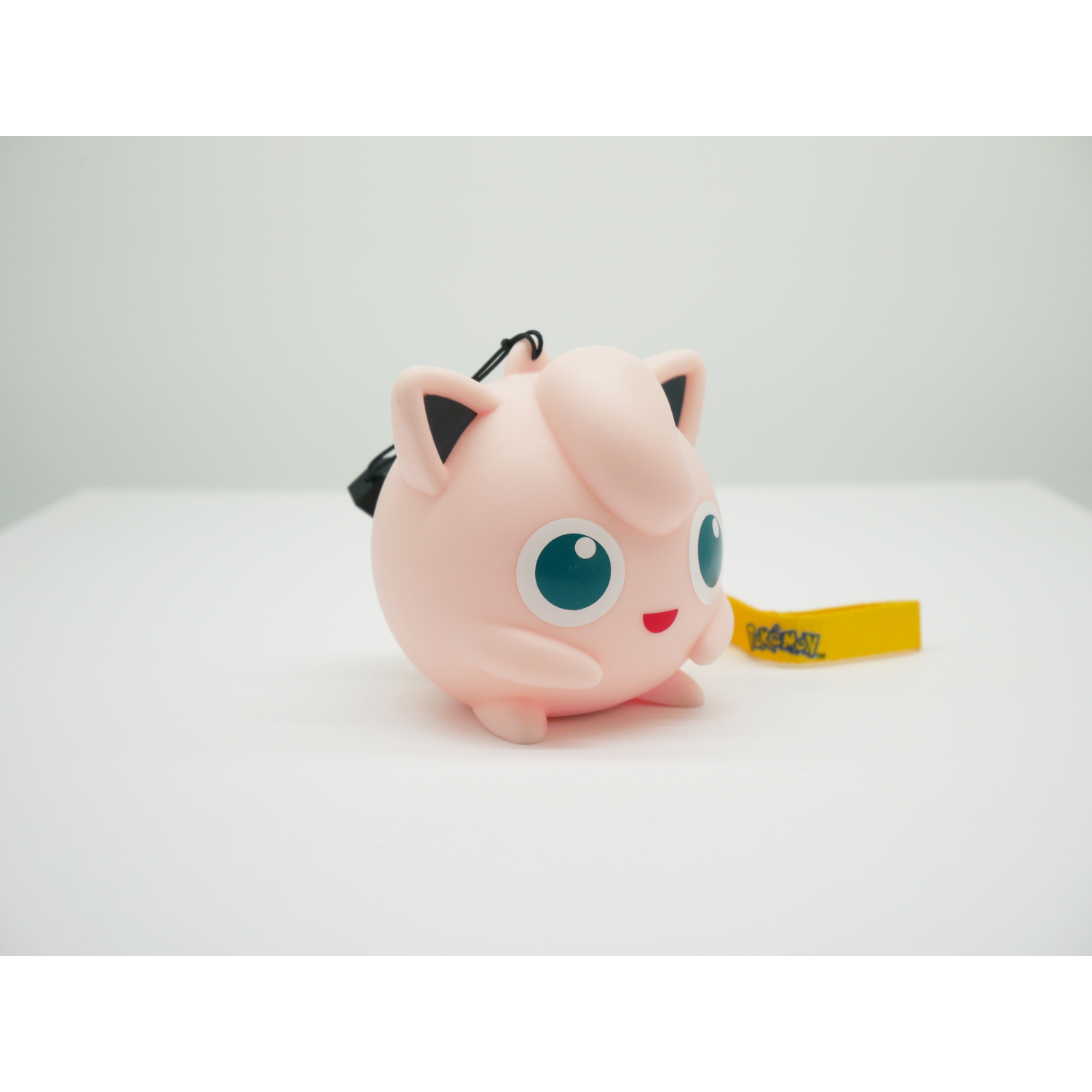 Een roze Jigglypuff figuur met blauwe ogen en een geel label.