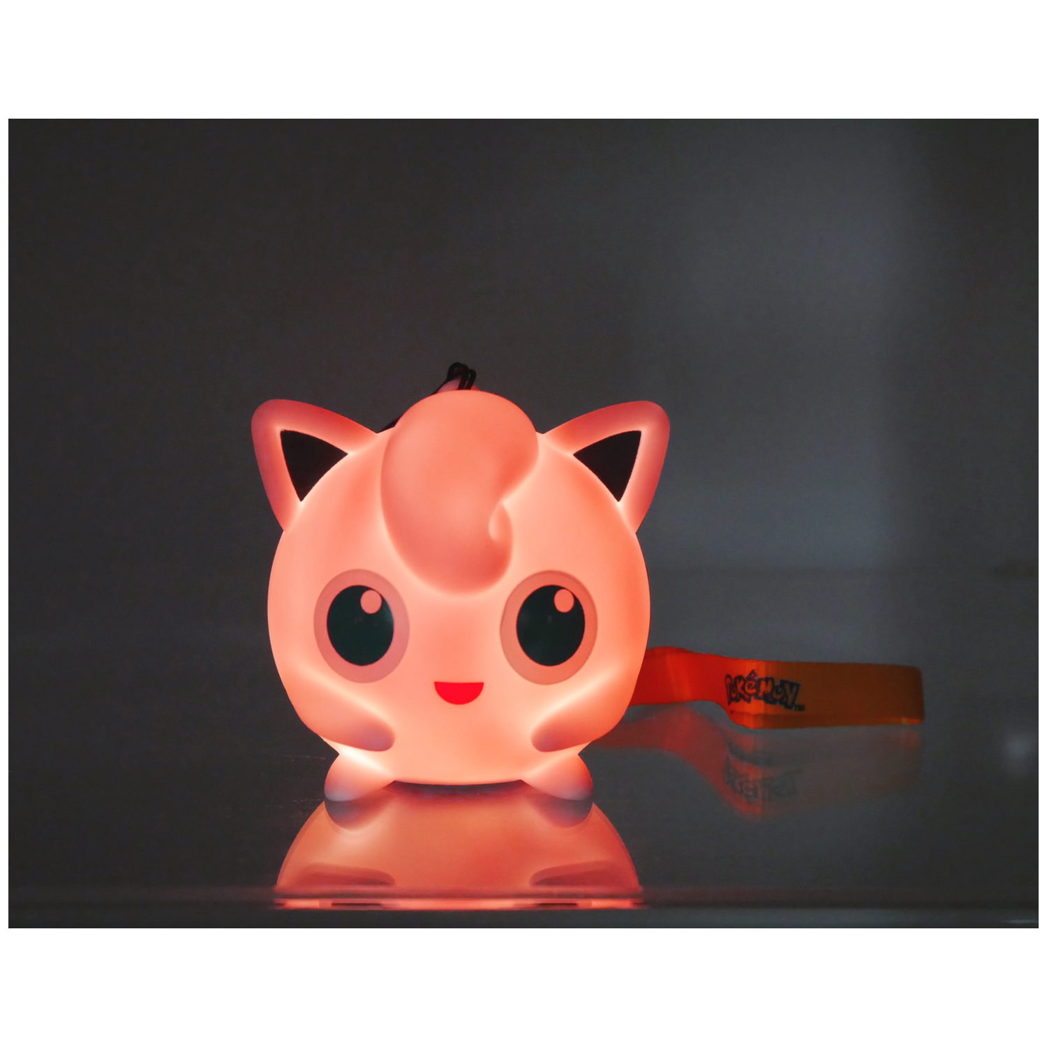 Een gloeiende roze Jigglypuff lamp met een Pokémon polsbandje.