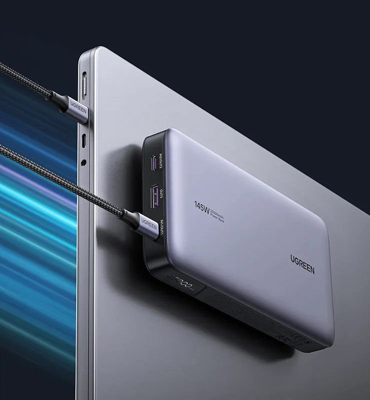 Graues UGREEN Powerbank mit 145W und 25000mAh lädt ein silbernes Laptop auf.