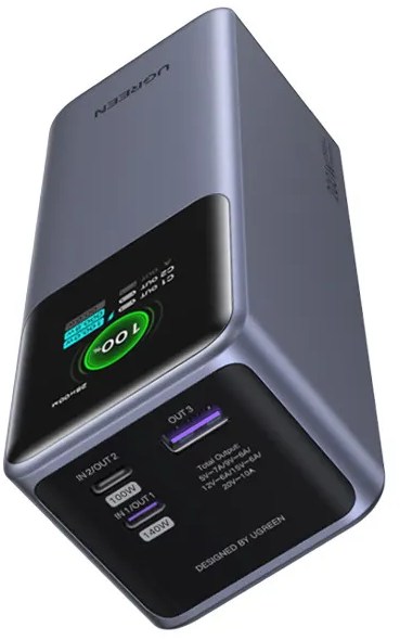 Une banque d'alimentation UGREEN grise affichant 100% de charge et des ports USB.