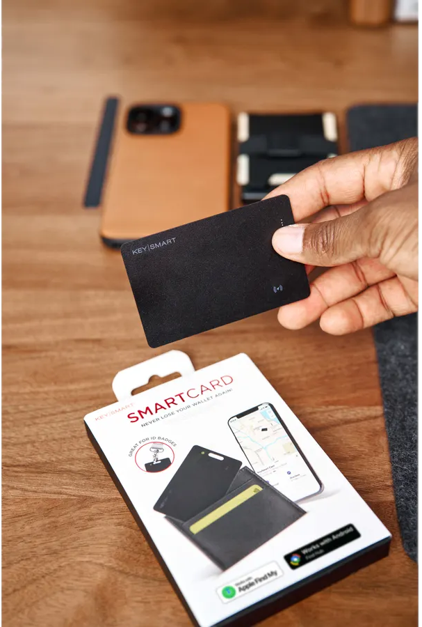 Eine Hand hält eine schwarze KeySmart-Karte über der Verpackung einer Smartcard.