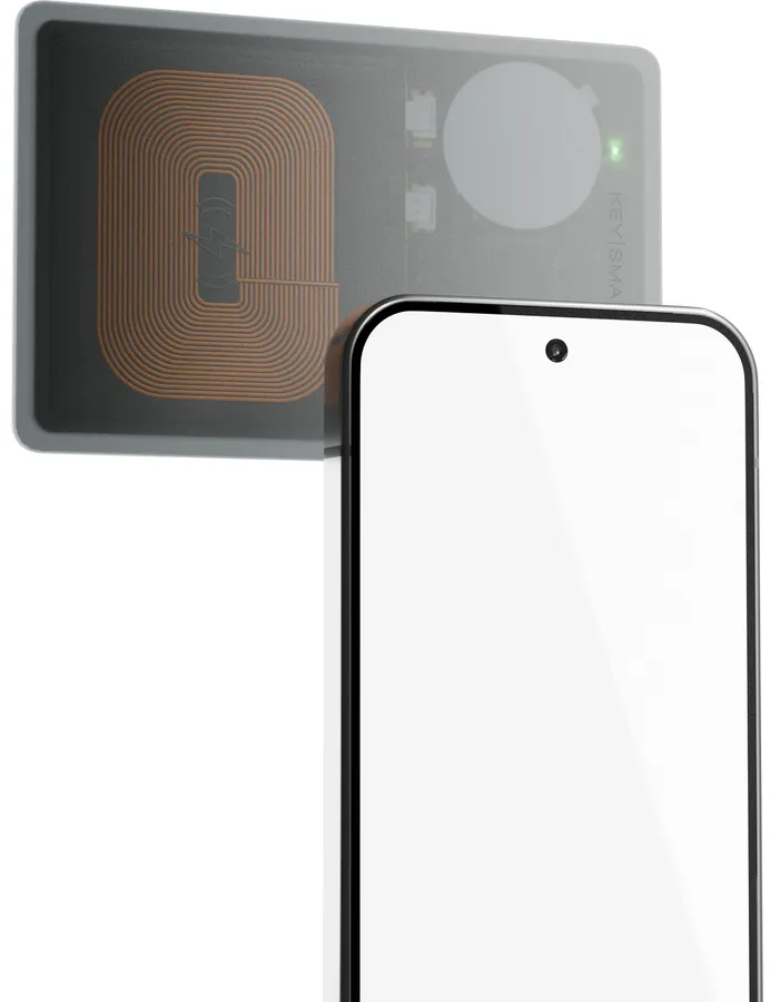 Ein Smartphone liegt vor einer Ladeplatte mit Kupferwicklungen und einem Blitzsymbol.