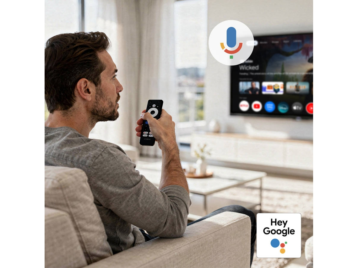 Un hombre se sienta en un sofá sosteniendo un control remoto. Se ve la pantalla de un televisor.