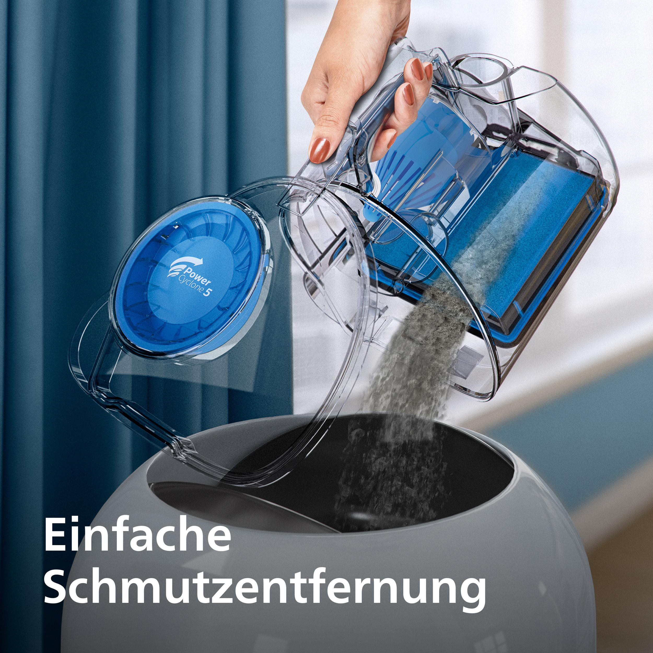 Eine Hand leert einen blauen Staubsaugerbehälter mit Staub in einen grauen Behälter.
