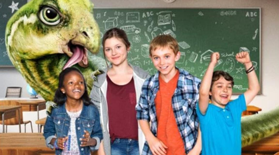 Ein grüner Dinosaurier mit Kindern in einem Klassenzimmer.