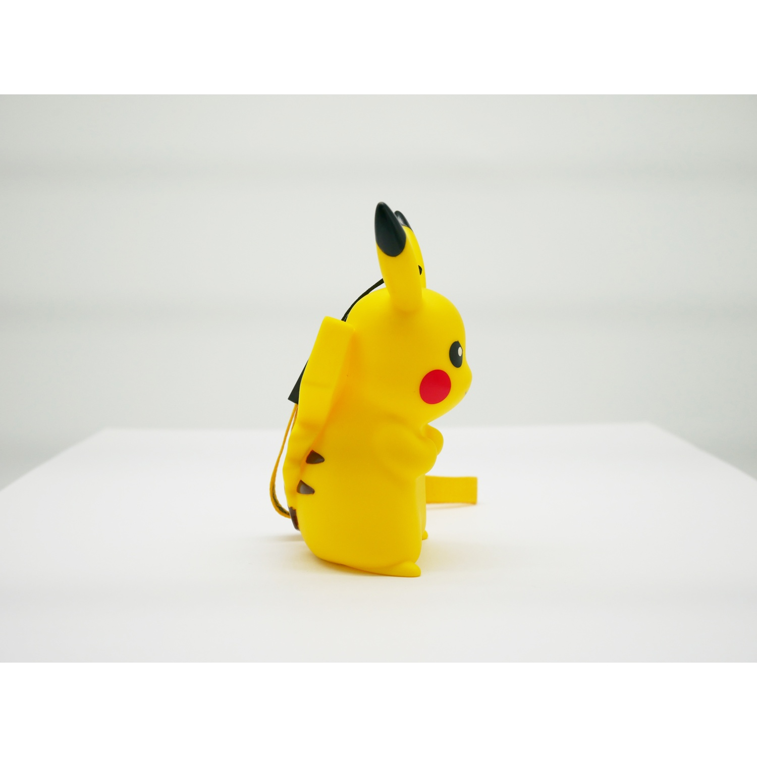 Een gele Pikachu-figuur met zwarte oren en rode wangen zit op een wit oppervlak.