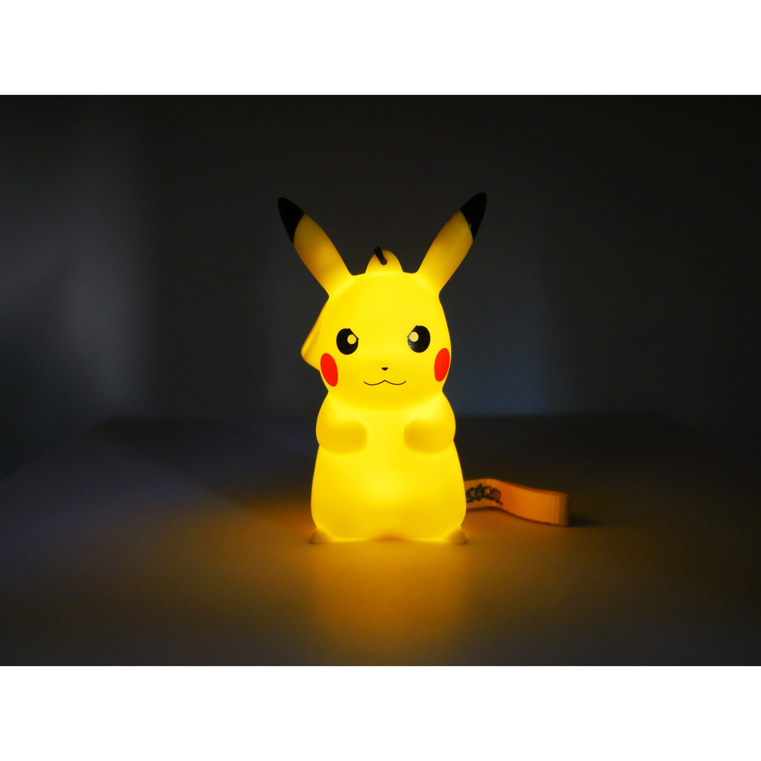 Een gloeiende Pikachu-lamp staat op een donker oppervlak.
