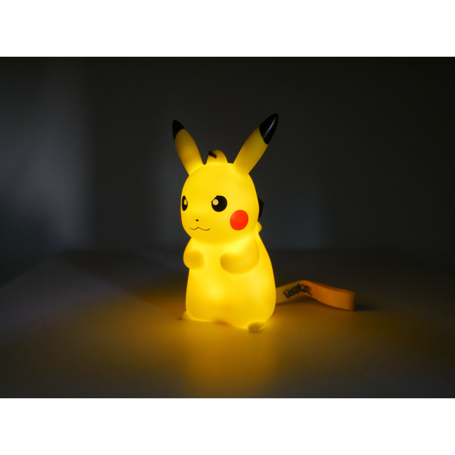 Een gloeiende Pikachu-figuur met een geel label staat in het donker.