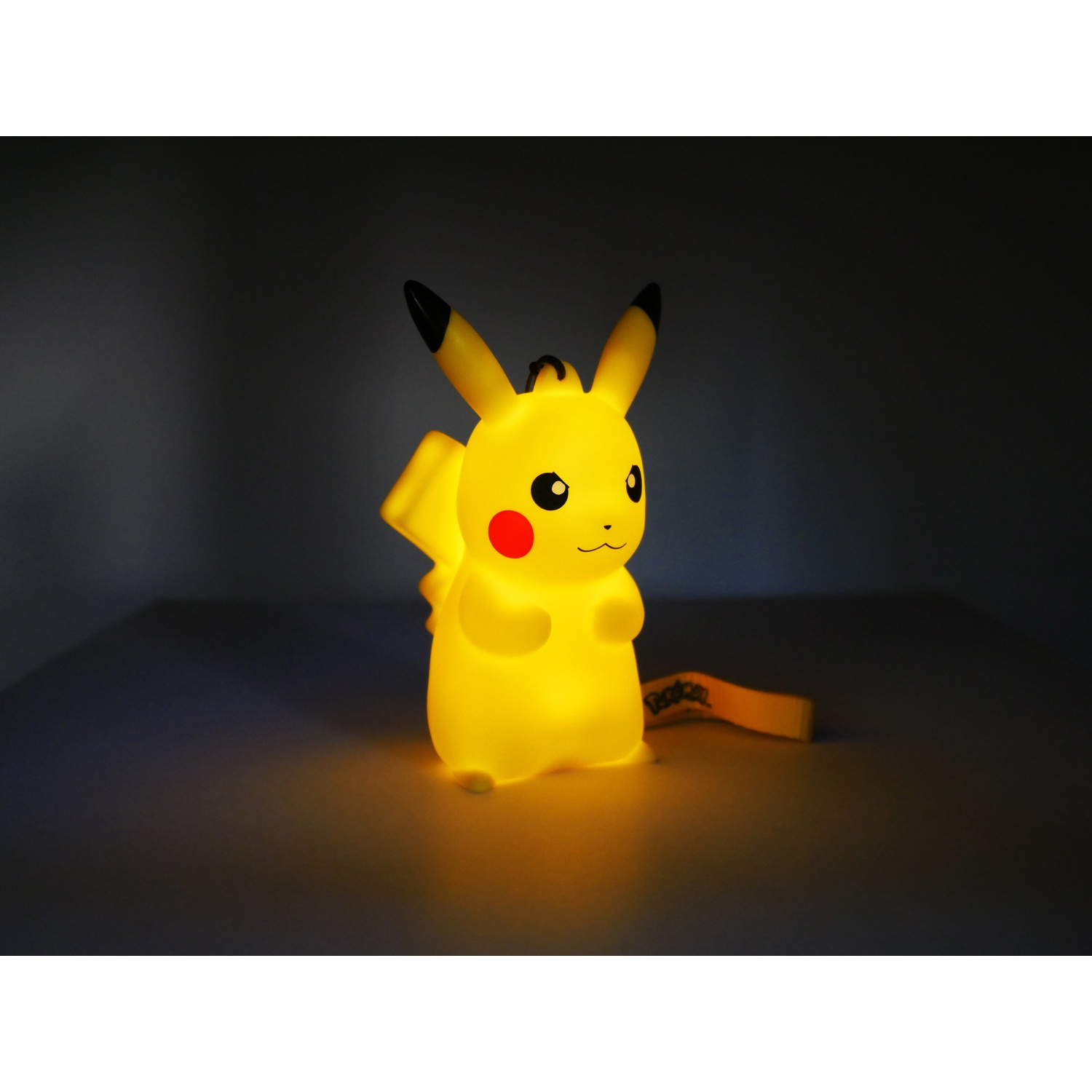 Een gloeiende gele Pikachu figuur met rode wangen en zwarte oortips staat.