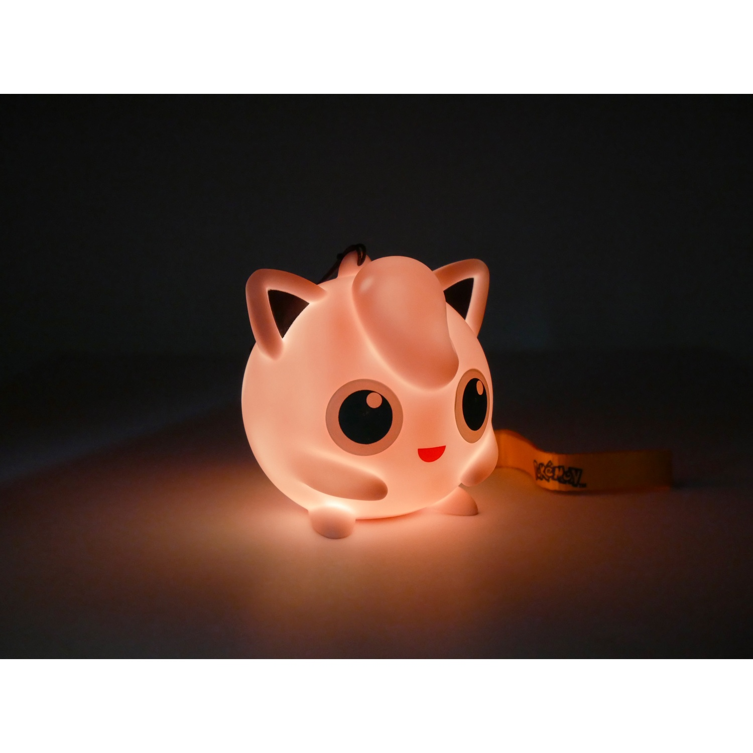 Een verlicht Jigglypuff-beeldje gloeit zachtjes op een donkere achtergrond.