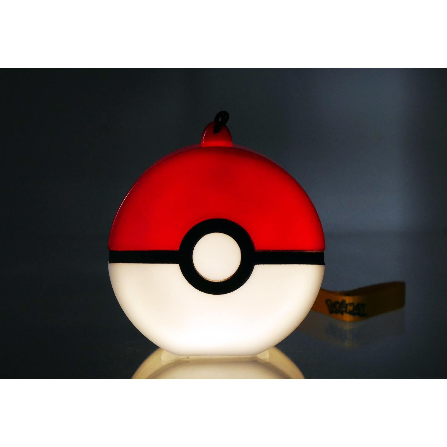 Gloeiende Pok&eacute;ball lamp met rode bovenkant, witte onderkant en zwarte band.