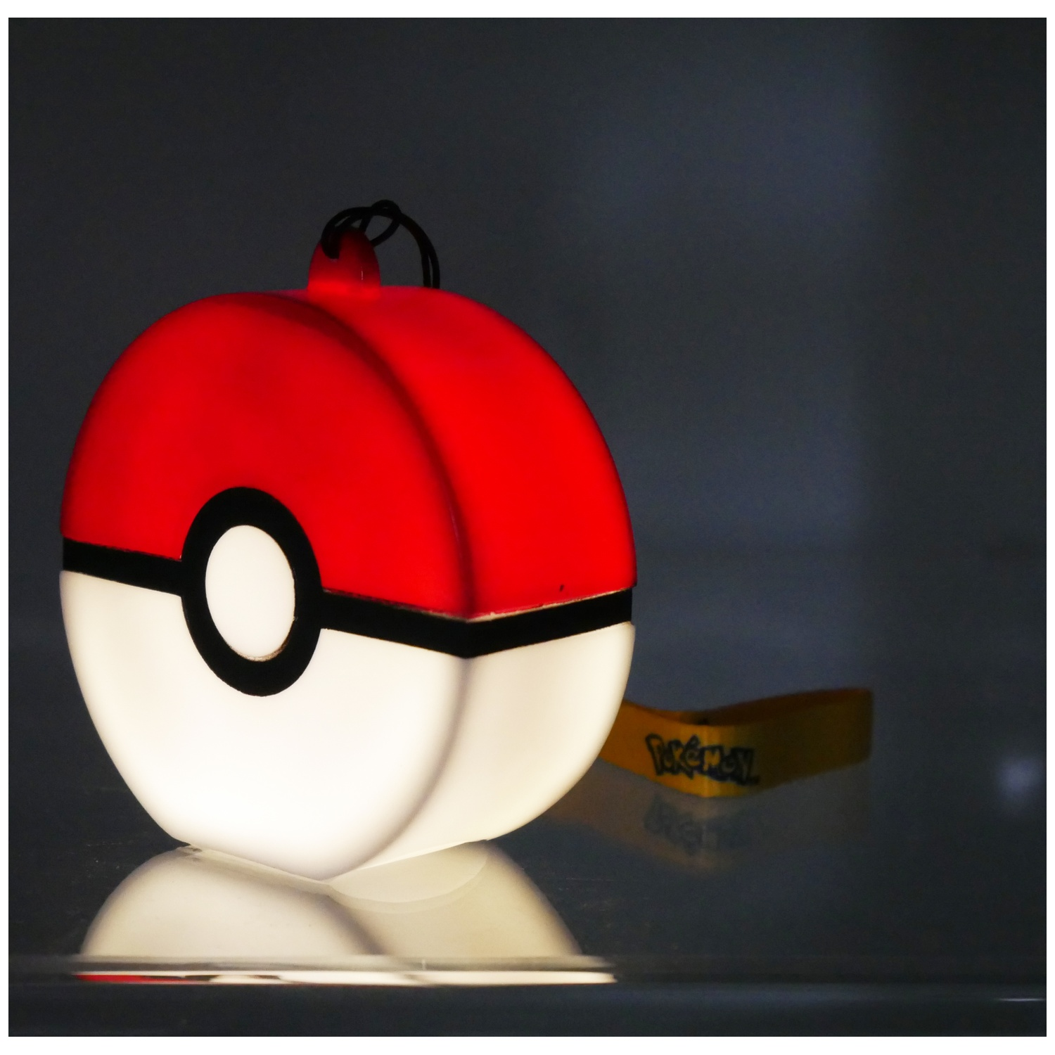 Een gloeiende Poké bal met een geel polsbandje ernaast.