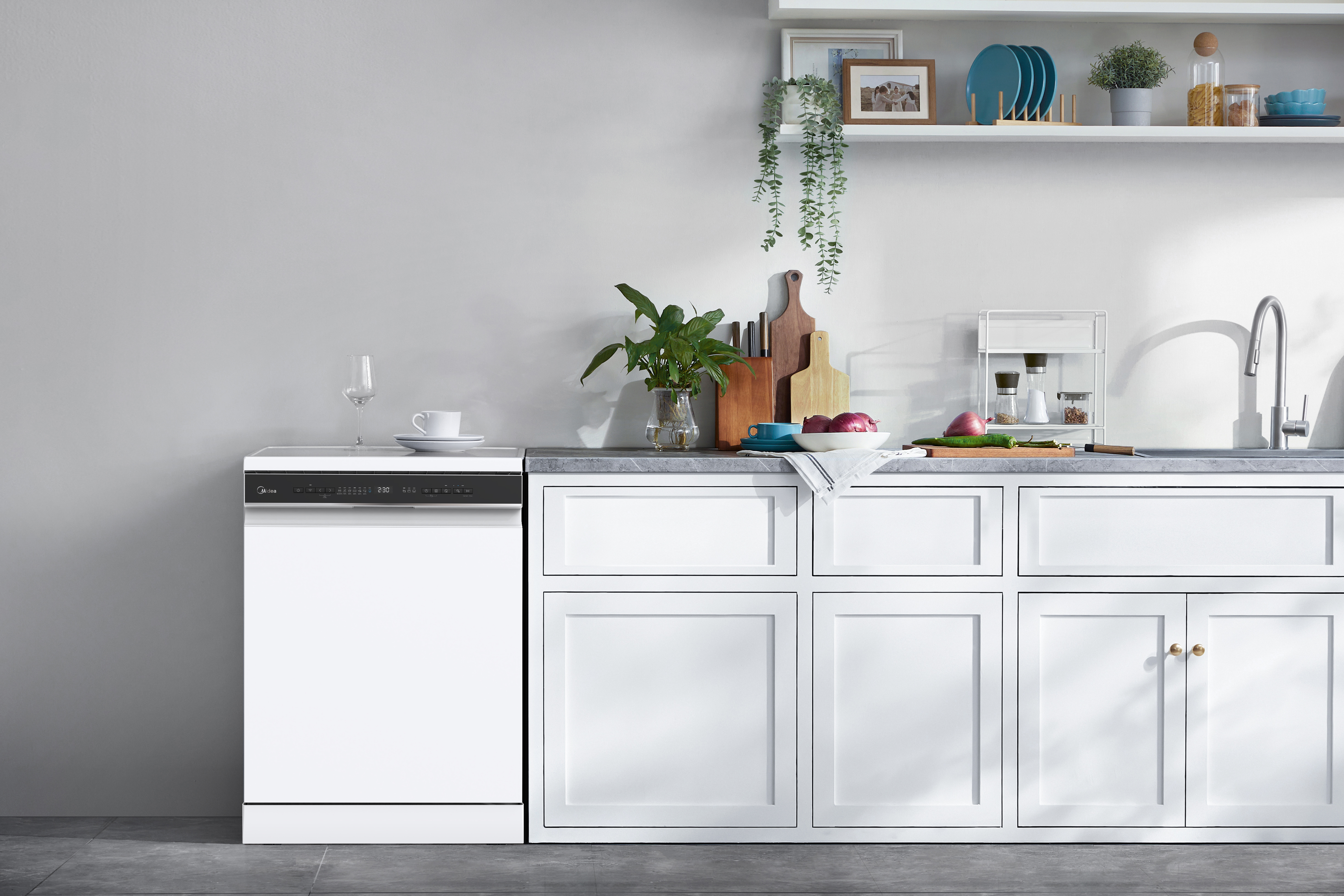 Un lavavajillas blanco junto a gabinetes de cocina blancos con algunos utensilios.