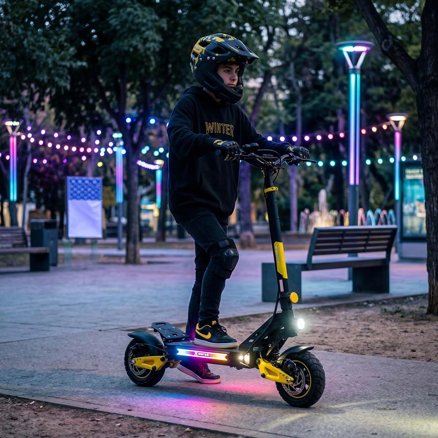 Chłopiec w kasku jedzie żółtym skuterem elektrycznym z kolorowymi światłami w parku.