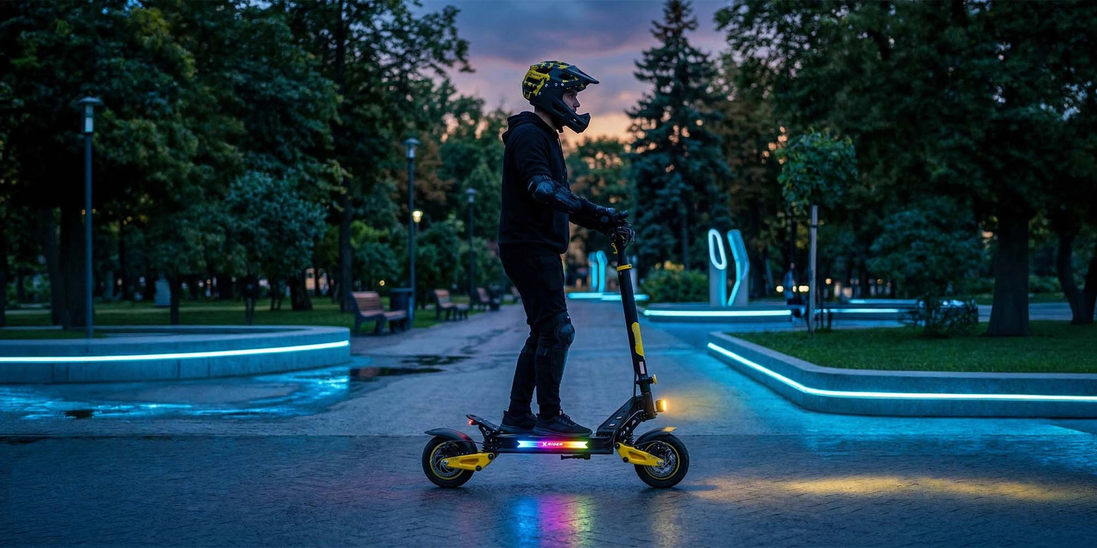 Osoba w kasku na hulajnodze elektrycznej z kolorowymi światłami w parku o zmierzchu.