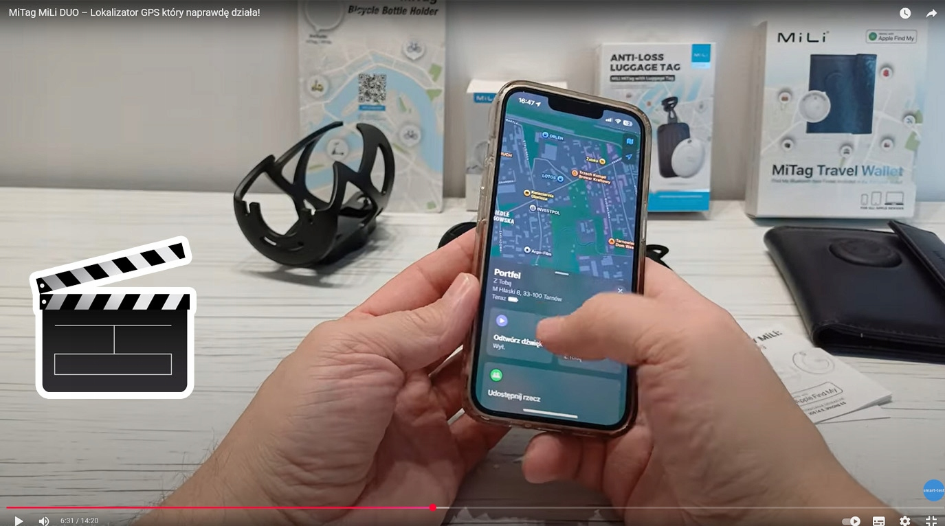 Dłonie trzymają telefon z mapą. Obok jest czarny uchwyt na bidon.