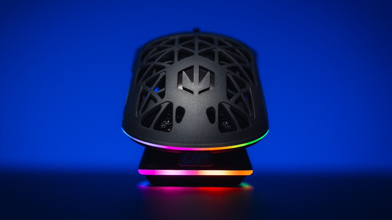 Czarna mysz gamingowa z ażurowym wzorem i podświetleniem RGB na niebieskim tle.