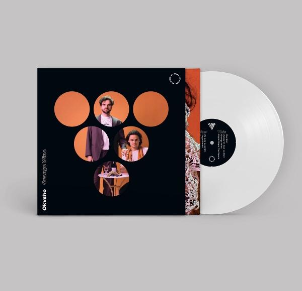 Schallplatte mit schwarzem Cover, das vier Porträts auf orangefarbenem Grund zeigt.