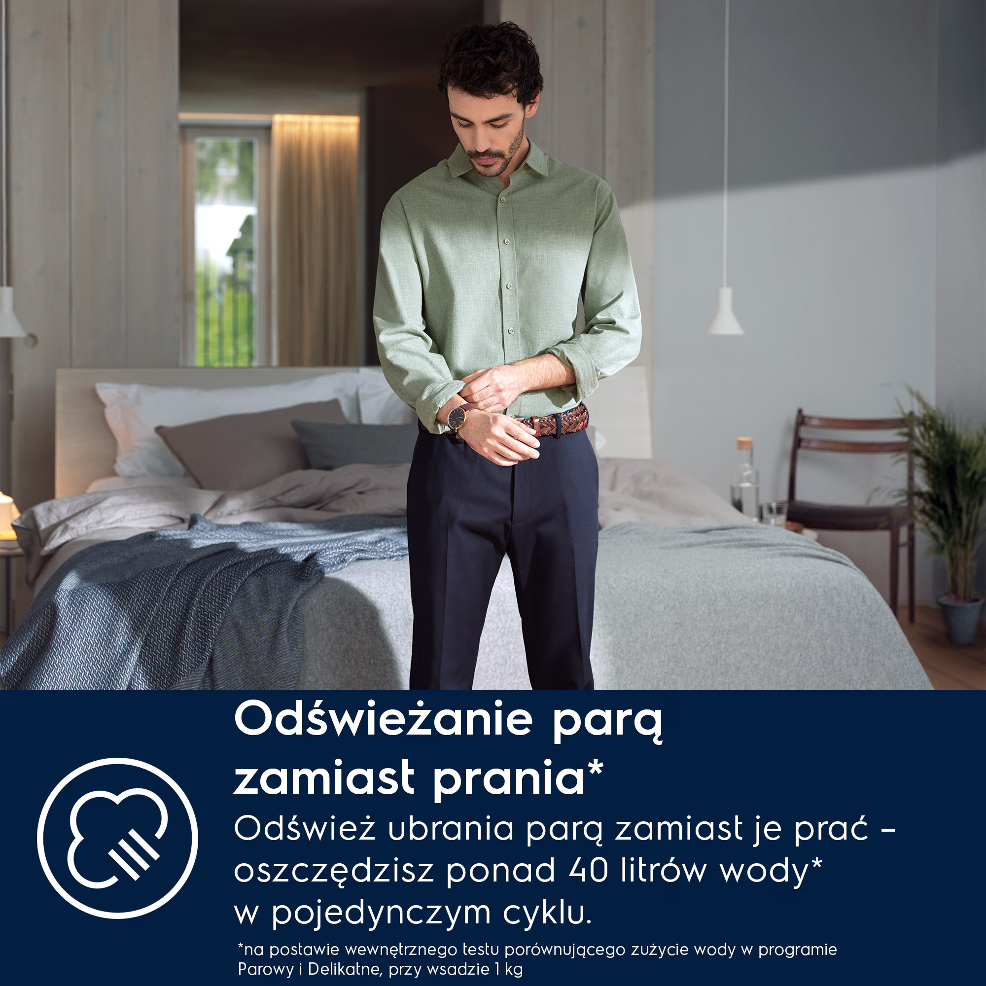 Mężczyzna w koszuli i ciemnych spodniach stoi przed łóżkiem. Poprawia zegarek.