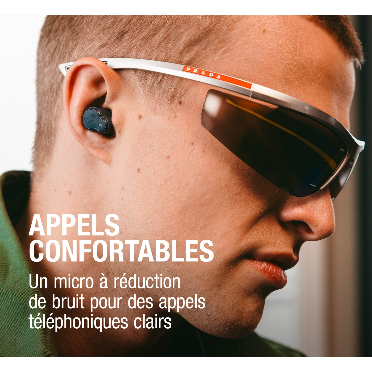 Gros plan d'un homme portant un écouteur et des lunettes de soleil Prada.