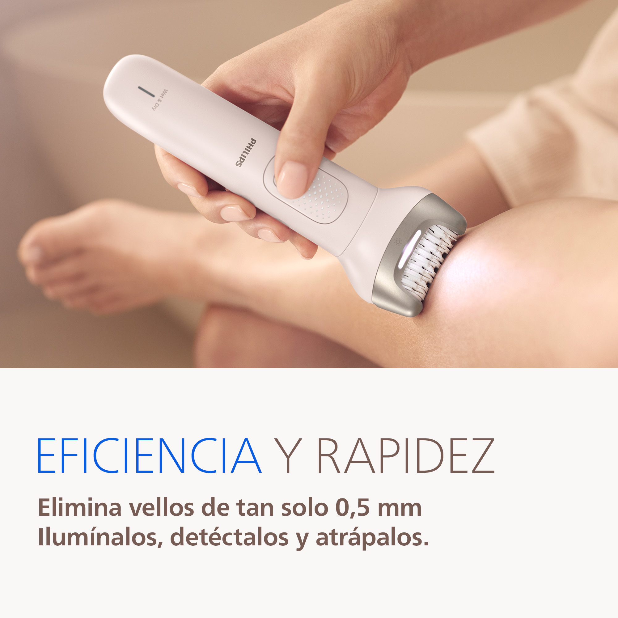 Una mano sostiene un depilador Philips blanco en la pierna de una persona.