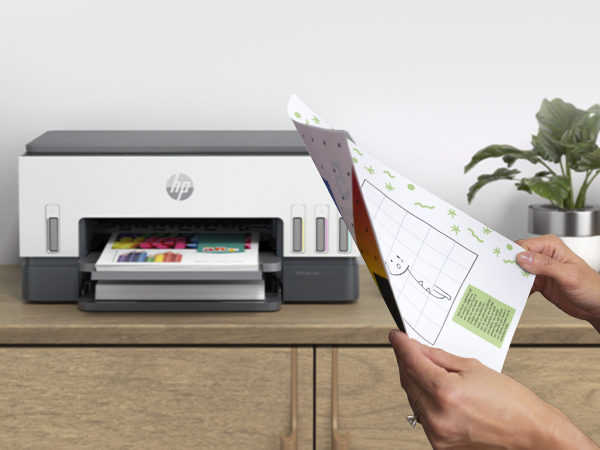 HP yazıcı, bir el çizimli bir kağıt tutarken renkli bir belge yazdırıyor.