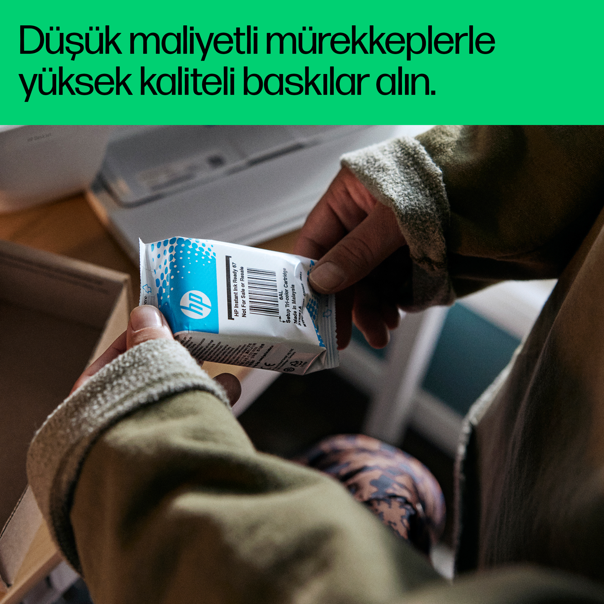 Eller açık bir kutunun üzerinde HP mürekkep kartuşu tutuyor.