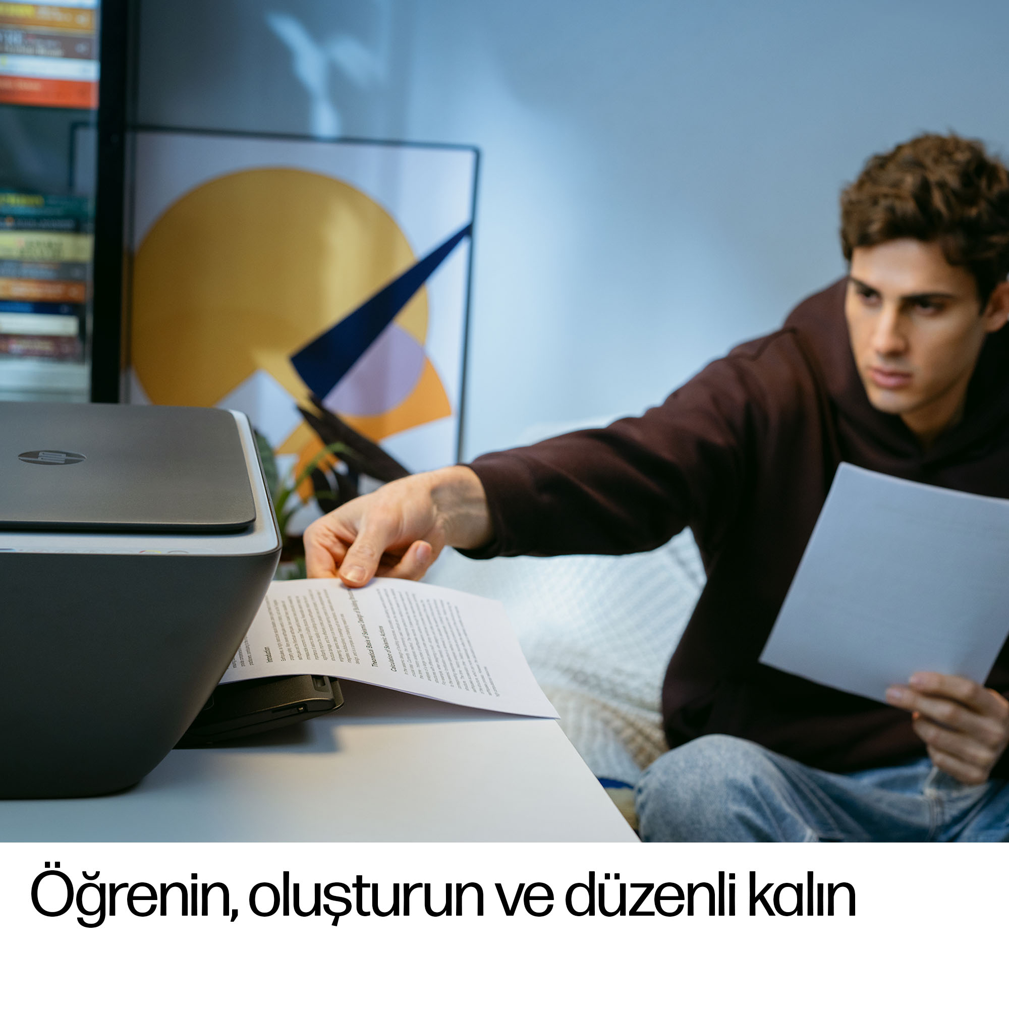 Bir adam yazdırmaya hazırlanıyor, bir yazıcıya kağıt yerleştiriyor.