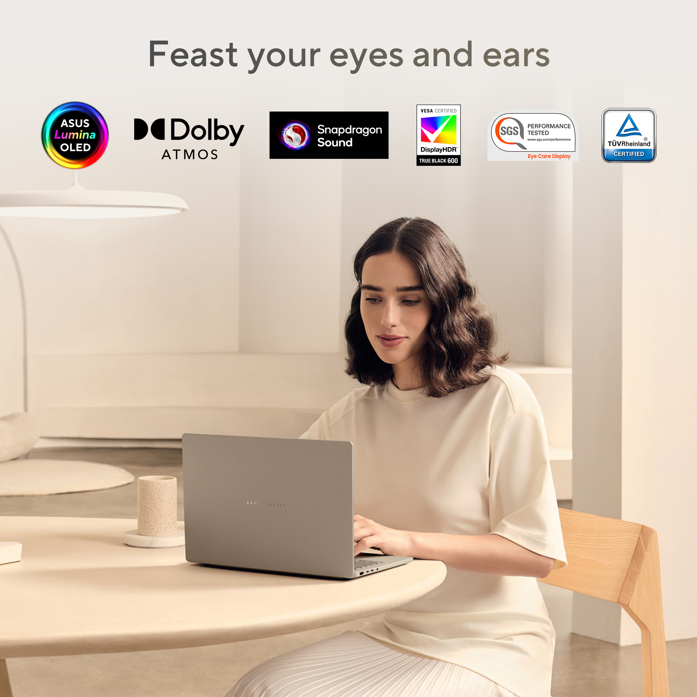 Vrouw met laptop op tafel, omringd door logo's voor ASUS Lumina OLED, Dolby Atmos, Snapdragon Sound en certificeringen.