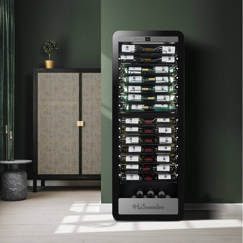 Ein schwarzer Weinkühlschrank mit vielen Flaschen, daneben ein Schrank mit Rattantür.