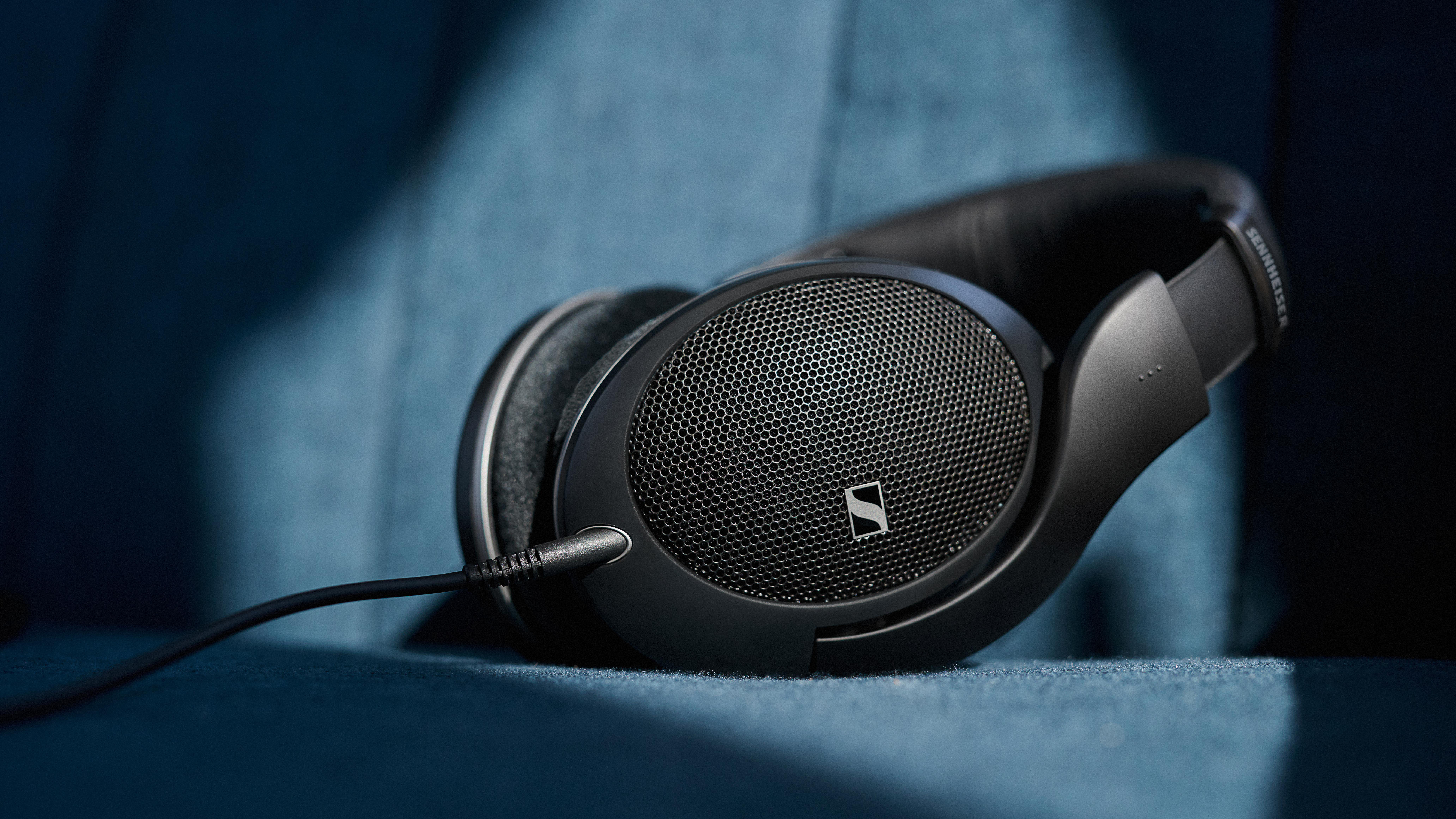 Schwarze Kopfhörer mit Kabel liegen auf blauem Stoff.