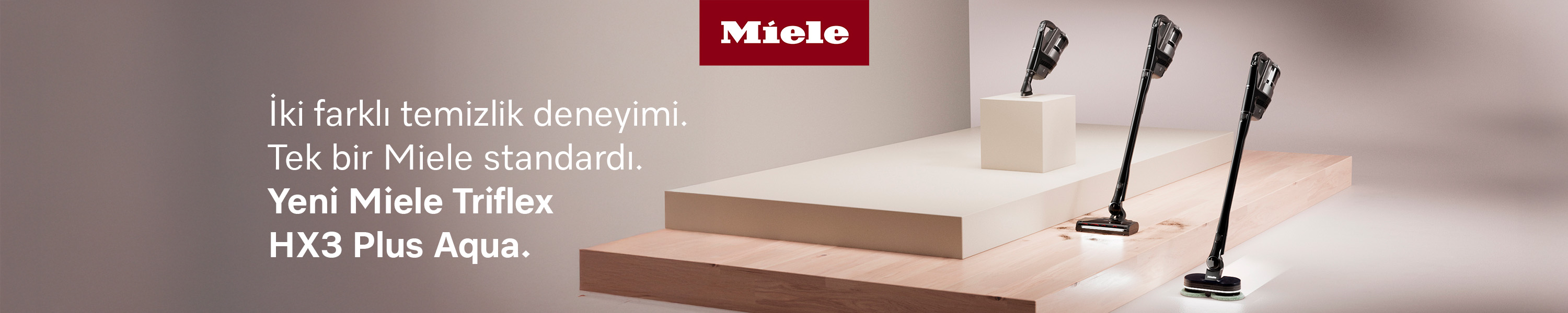 Üç Miele Triflex HX3 Plus Aqua elektrikli süpürge kaideler üzerinde. Üstte Miele logosu.