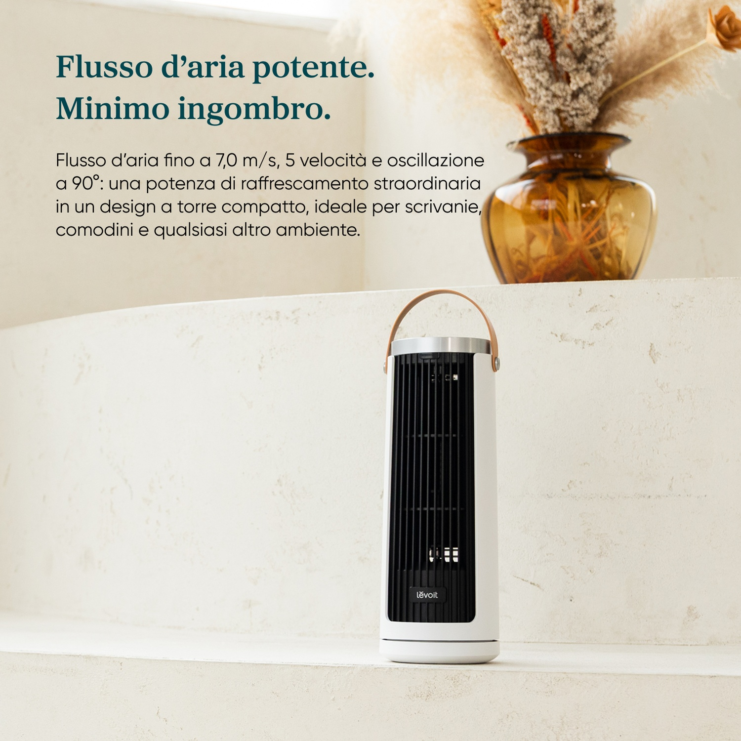 Un ventilatore a torre bianco su una mensola accanto a un vaso di fiori secchi.