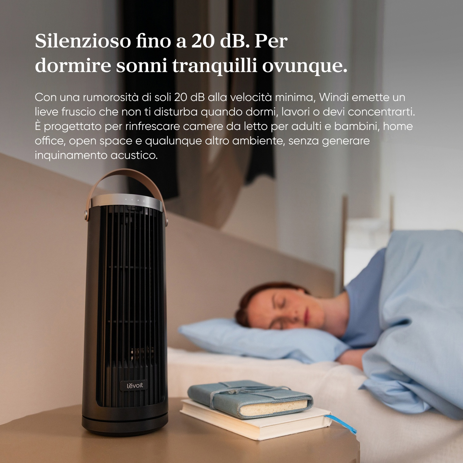 Ventilatore a torre nero accanto a una ragazza che dorme nel letto.