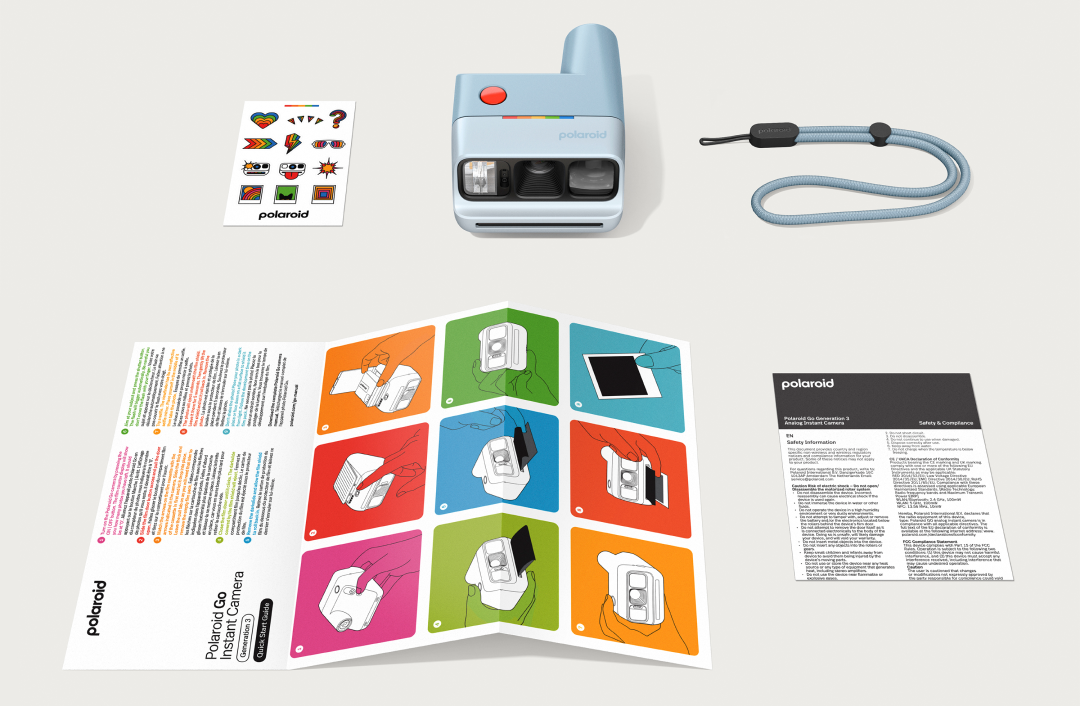 Polaroid Go fényképezőgép, matricák, szíj és használati útmutatók laposan elrendezve.