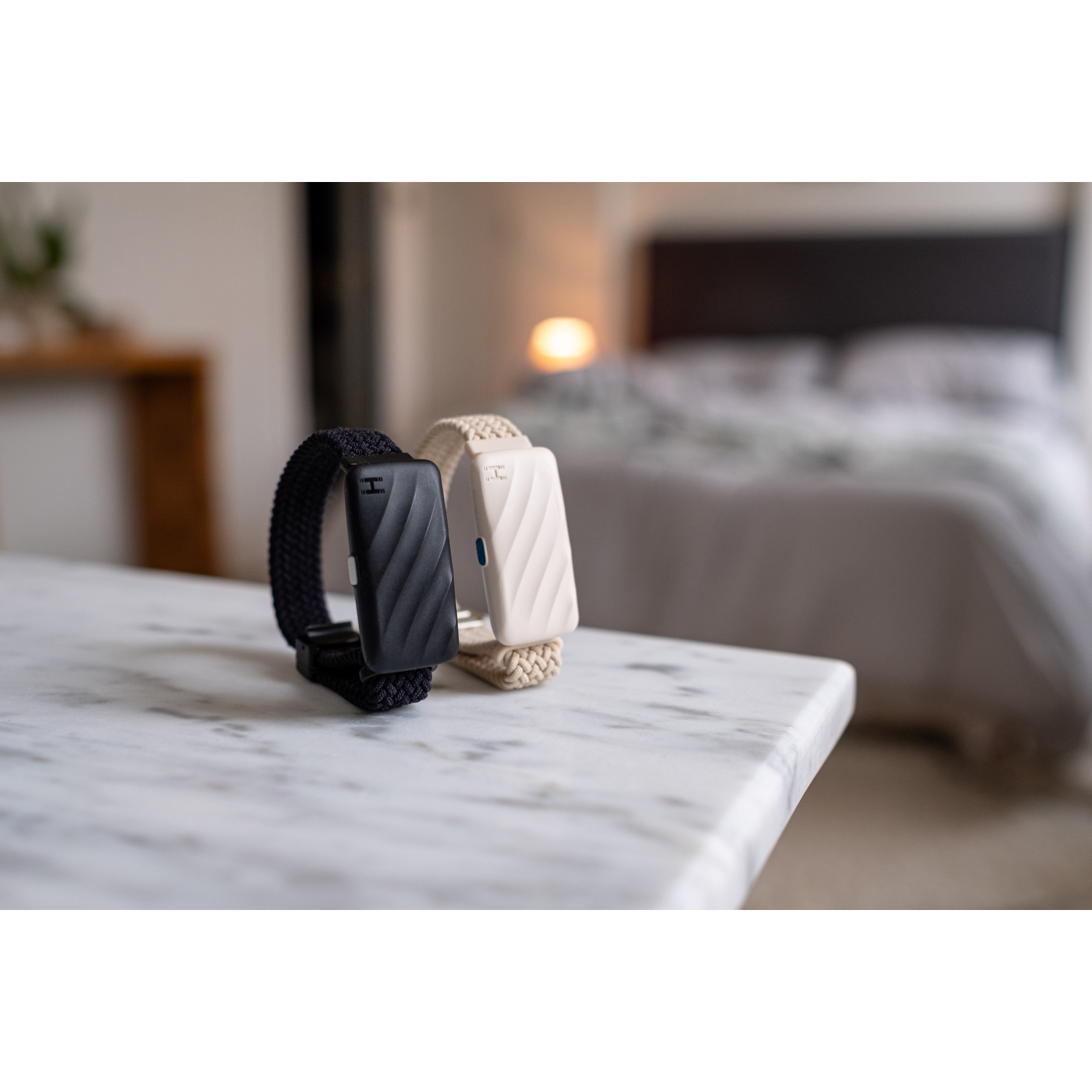 Two smartwatches, one black and one white, rest on a marble table.