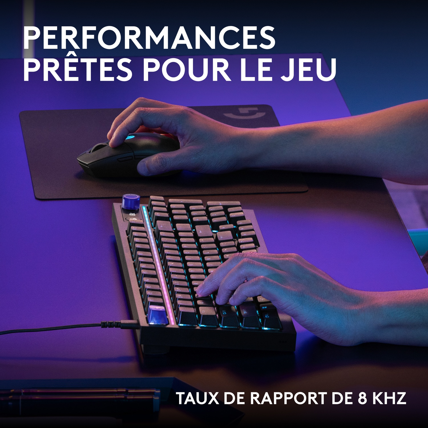 Mains sur un clavier et une souris, éclairées par une lumière bleue et violette.
