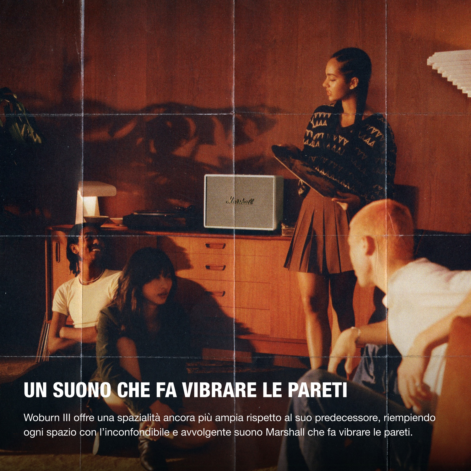 Quattro giovani ascoltano musica in una stanza con mobili retrò e un altoparlante Marshall.