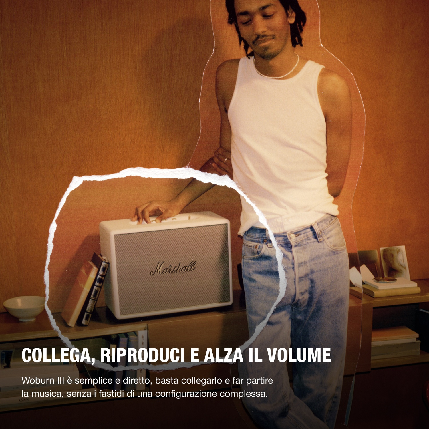 Uomo con canotta bianca e jeans accanto a uno speaker Marshall bianco.