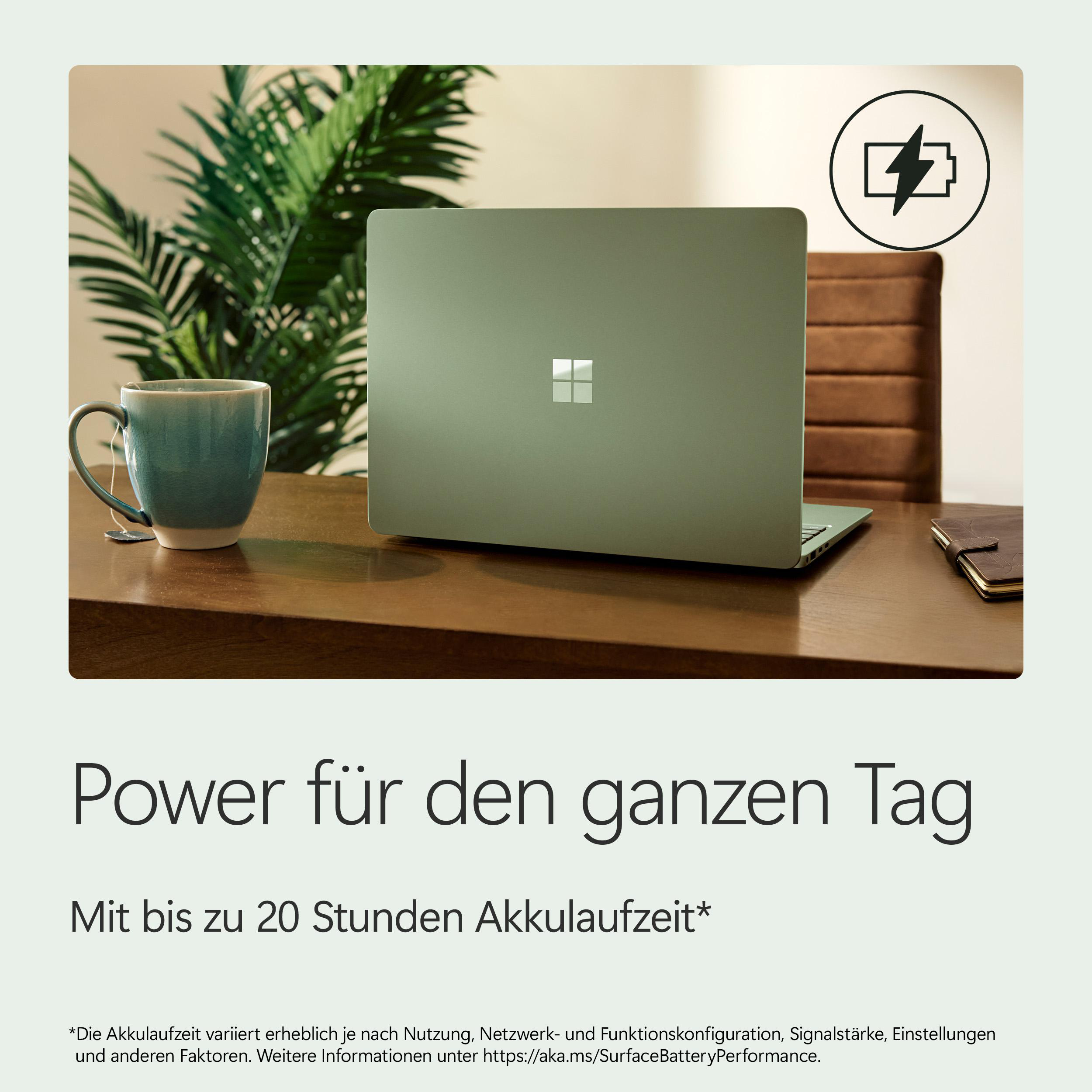 Ein grüner Laptop steht auf einem Schreibtisch neben einer Tasse und einer Pflanze.