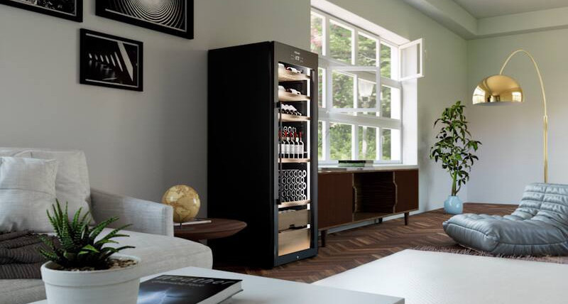 Ein schwarzer Weinkühlschrank mit Flaschen steht in einem stilvollen Wohnzimmer.