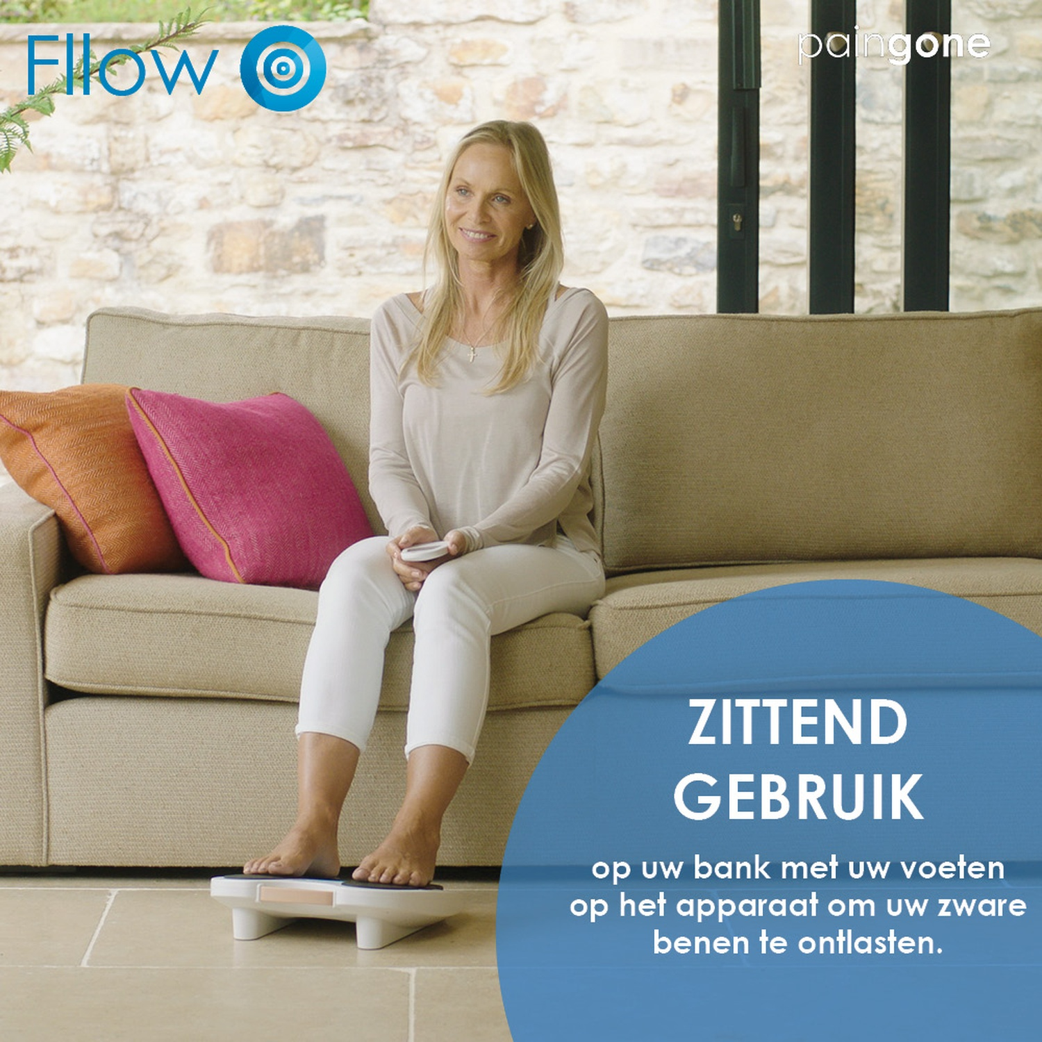 Een vrouw zit op een bank en gebruikt een voetapparaat om haar benen te ontlasten.