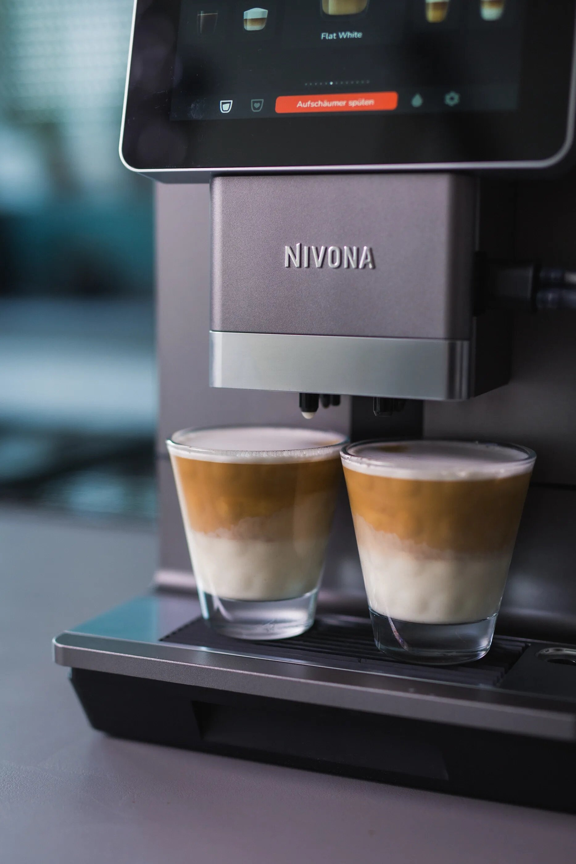 Ekspres do kawy robi dwa warstwowe latte w szklankach.