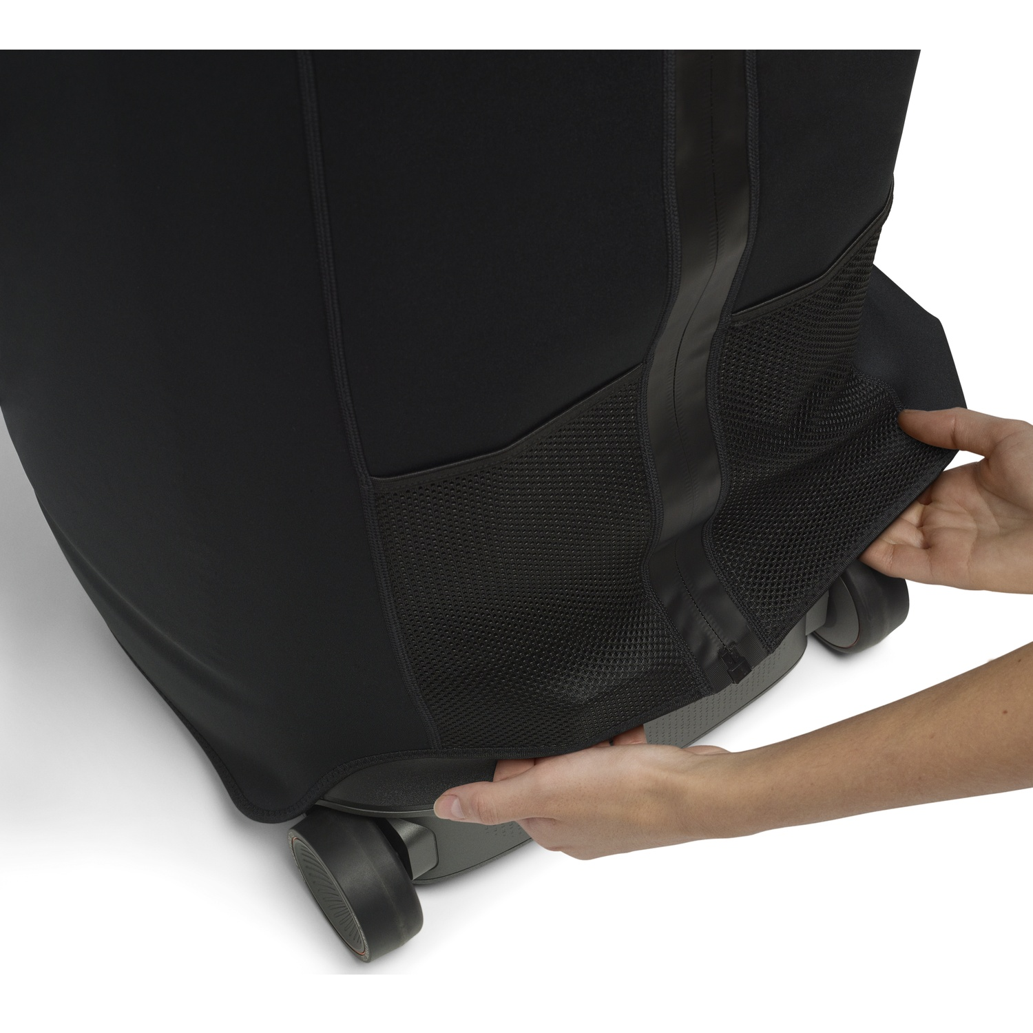 Mains ajustent housse en tissu noir avec poches en filet sur une valise grise à roulettes.