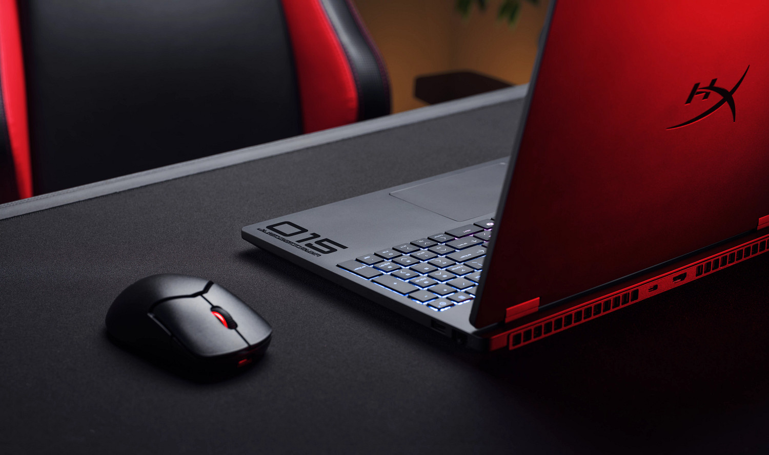Czerwony laptop gamingowy z podświetlaną klawiaturą i myszką na biurku.