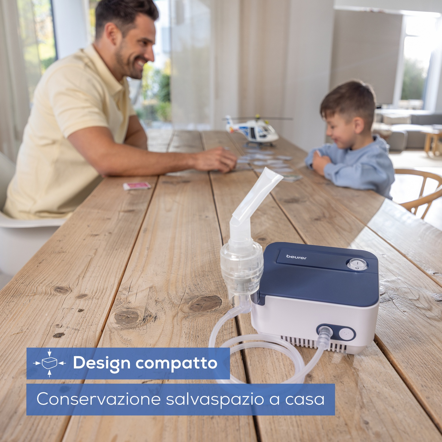 Padre e figlio a un tavolo con un nebulizzatore Beurer. Design compatto.