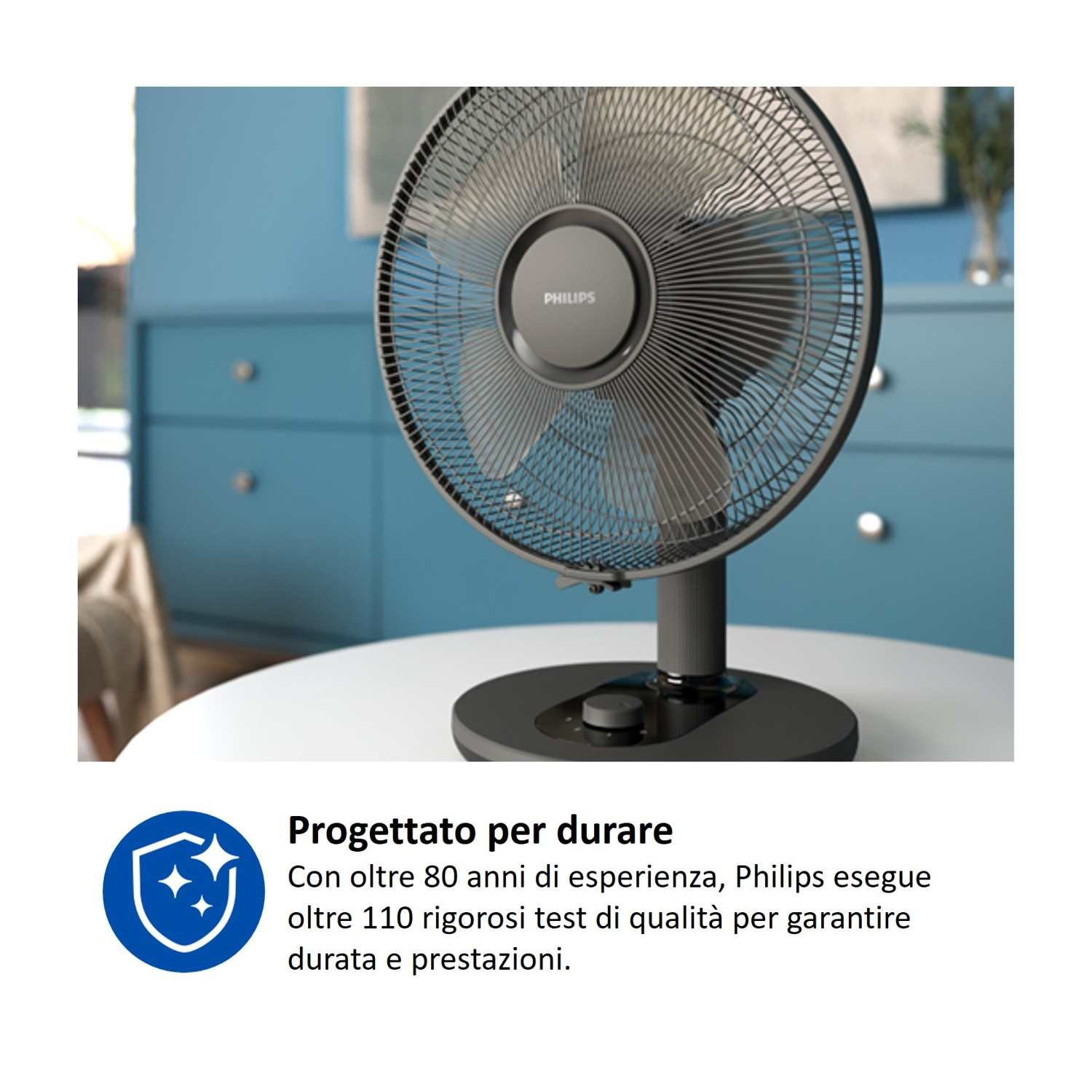 Un ventilatore scuro su un tavolo rotondo davanti a un mobile blu.