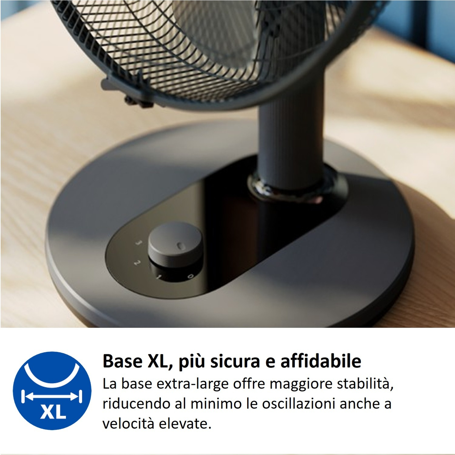 Ventilatore grigio scuro con base XL e manopola di controllo su tavolo in legno.