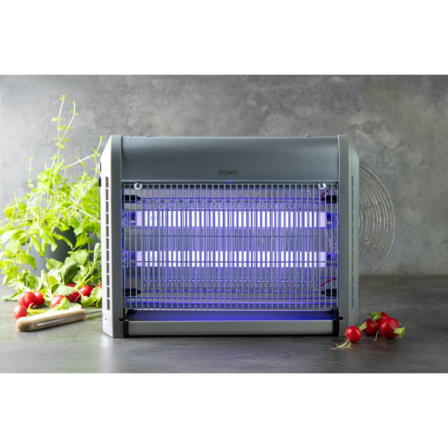 Een grijze insectendoder met blauwe UV-lampen, naast radijsjes en een mes.